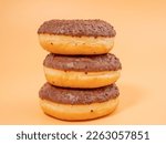 Chocolate donut with chocolate chips on an orange background. close-up.