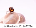 Small photo of Gemstone ring gift concept. Close-up of Cinnamon stone ring on seashell with white background