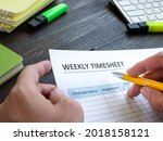 Small photo of Man filing in weekly timesheet for employee in the office.