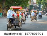 Cyclo driver taking tourist visiting old quarter on street in Hanoi