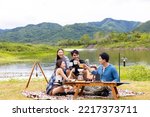 Small photo of Group of Asian people enjoy and fun outdoor lifestyle hiking and camping together on summer travel vacation. Man and woman friends having breakfast drinking brewed coffee near the tent in the morning.