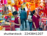 Asian woman mother and daughter holding shopping bag during buy home decorative ornament for celebrating Chinese Lunar New Year festival at Bangkok Chinatown street market. Chinese culture concept.