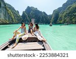 Small photo of Group of Young Asian woman friends sitting on the boat passing island beach lagoon in summer sunny day. Attractive girl enjoy and fun outdoor lifestyle travel on summer holiday vacation in Thailand