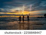 Group of Young Asian woman friends dancing and playing sparklers firework together at tropical beach in summer night. Happy girl enjoy and fun outdoor lifestyle nightlife party on holiday vacation.