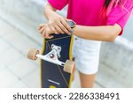 Portrait of Asian woman holding longboard skate during skating at park on summer vacation. Attractive girl have fun urban active lifestyle practicing outdoor sport skateboarding in the city at sunset.