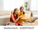 Young Asian woman friends watching movie on television together in living room at home. Attractive girl enjoy and fun indoor activity lifestyle spending time together on summer holiday vacation.