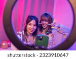 Happy Asian generation z woman friends vlogger influencer content creator enjoy and fun using smartphone online live streaming viral video cover dance on social media application in bedroom at home.