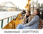 Happy Asian woman friends sitting on ferry boat crossing Sydney harbour in Australia. Attractive girl enjoy and fun urban outdoor lifestyle shopping and travel in the city on holiday vacation.