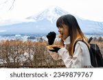 Asian woman eating Japanese street food Takoyaki during travel lake Kawaguchi and Mt Fuji. Attractive girl enjoy outdoor lifestyle travel Japan landmark famous place on winter holiday vacation.