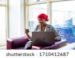 African female businesswoman shopping for home using laptop computer holding credit card