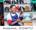 mage of Beautiful young black teenage african female shoe entrepreneur on apron folding working 