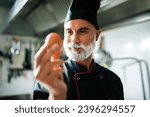 Small photo of Close-up of a male chef with a discerning eye examining an egg in a professional kitchen