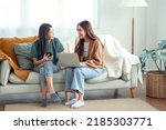 Small photo of Two woman communicate with their friends and classmates via video link using a laptop and smartphone in the living room. Friends, friendship, time together