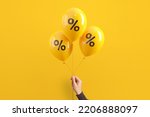 Hand of woman holding balloons with percent on yellow background, Minimal, Sale and discount.