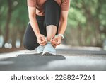 Small photo of Close up - Running shoes runner woman tying laces for summer run in forest park. Jogging girl exercise motivation health and fitness exercise. copy space.