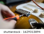 Small photo of Adjusting the intonation of electric guitar by screwing a screw at a guitar bridge