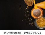 Small photo of A ladle of honey on the background of a honeycomb of a bee. Honey tidbit in a glass jar honey spoon, bee bread and a honeycomb of wax on a black background. Healthy food concept.