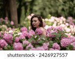 Small photo of Hydrangeas Happy woman in pink dress amid hydrangeas. Large pink hydrangea caps surround woman. Sunny outdoor setting. Showcasing happy woman amid hydrangea bloom.