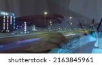 Small photo of Image of hands working on laptop over sped up traffic in city at night. business and communication technology concept digitally generated image.