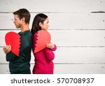 Angry couple holding broken heart against wooden background