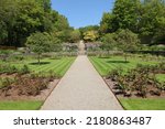 A gravel path runs between two verdant lawns before rising up several flights of steps and terraced gardens in the formal gardens of an English country house on the edge of Dartmoor National park