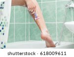 Close up of woman shaving legs in bathroom. Close up of legs of healthy girl shaving it carefully. She has shaving cream on her legs.