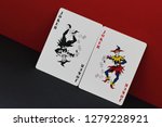  Game of imagination. Card allegory is red and black as symbol of opposites and contradictions in world. Red and black joker on contrasting red and black background.