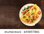 A photo of an omelette with cherry tomatoes, parsley. and grated cheese, shot from above on a rustic wooden texture with a place for text
