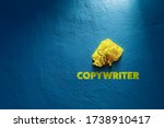 Copywriter propagation concept. Yellow crumpled paper (symbol of unsuccessful text without idea) and text copywriter on blue background.