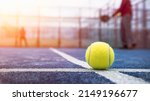 Small photo of Yellow ball on floor behind paddle net in blue court outdoors. Man who playing padel tennis. Caucasian player sportsman hitting balls. Racquet sport game concept.