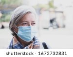 Small photo of close up of face of mature woman looking away wearing medical mask prevention coronavirus or covid-19 or another type of virus - senior portrait and close up with medicine mask on the face