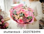 great bouquet of pink chrysanthemum hydrangea and roses wrapped in paper in woman hands. Floral shop concept. Handsome fresh bouquet.