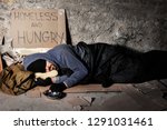 Small photo of Houseless man sleeping on the street with alms box