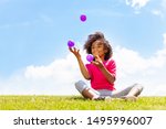 Small photo of Positive happy girl juggle balls on the grass