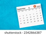 September 2023 and wooden push pin on blue background.