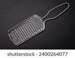 Beautiful small metal kitchen grater with handle on a dark textured background