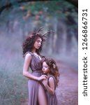 Small photo of fairy mother of a deer on path hugs her child and holds her hand, closed her eyes and listen to the sound of a misty forest, in long brown dresses with a purple tinge, cutout shows the leg of a woman
