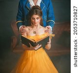 Woman princess holding a book without title cover design reads the text. Fantasy man enchanted prince hugging a beautiful lady by shoulders. Girl in yellow medieval historical dress vintage gown