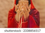 Small photo of Mystery arabic woman beauty golden mask veil niqab hide face hands close-up with gold metal rings jewelry. Fantasy girl art photo fashion model red dress abay asilk scarf. Sand dunes desert