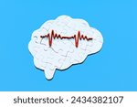 Small photo of Human brain-shaped puzzle overlaid with an electroencephalogram (EEG) graph, set against a calming blue backdrop. Neuroscience, neurology, brain health, and cognitive research concept.
