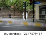Small photo of Shanghai, China - April 20 2022: Two workers in protective gear stand on an empty street corner during Shanghai's COVID-19 Lockdown continues