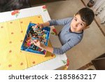 A Caucasian boy looks at the camera showing the handfuls of sweets he has taken from a candy box.