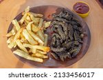 Stir fried edible insects of the species Cirina Forda, french fries, lettuce leaves and ketchup, exotic alternative food,