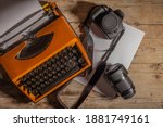 Small photo of Antique typewriter with modern photographic equipment on a rustic wooden table with white papers. Equipment of an ancient documentarian in overhead view.