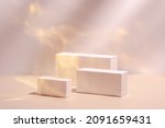 Small photo of Abstract surreal scene - empty stage with three rectangle white podiums on pastel pink and gold colored background. Pedestal for cosmetic product packaging mockups display presentation