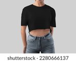 Mockup of black crop top on girl in gray jeans, blank t-shirt canvas bella, for design, branding, front view. Fashion clothes template, shirt isolated on background. Women's textured apparel close-up