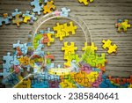 Small photo of A magnifying glass on Russia in a world map puzzle with puzzle pieces missing and disjointed