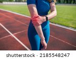 Small photo of Sports and healthy lifestyle. A woman injured her elbow while exercising at a sports stadium. Pain in the elbow, arm. Ligament stretching.A young female runner suffers from pain in her elbow.