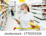 Small photo of A woman in a mask during a pandemic chooses products and buys in a supermarket. Countervailing measures in pandemic. Grocery offline shopping.