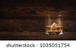 Whisky or whiskey or bourbon with ice on wood background